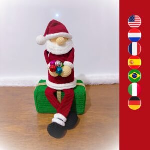 gehaakte kerstman die op een gehaakte cadeaudoos zit